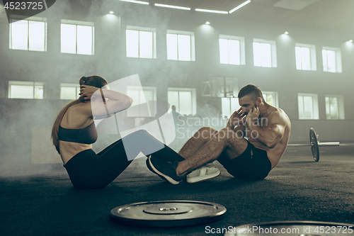 Image of Man and woman during exercises in the fitness gym. CrossFit.