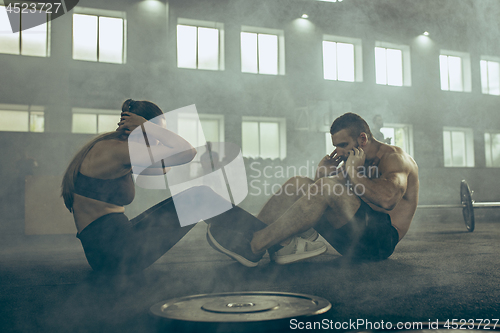 Image of Man and woman during exercises in the fitness gym. CrossFit.