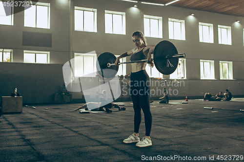 Image of Fit young woman lifting barbells working out in a gym