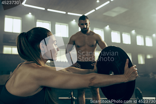 Image of Fit young woman lifting barbells working out in a gym