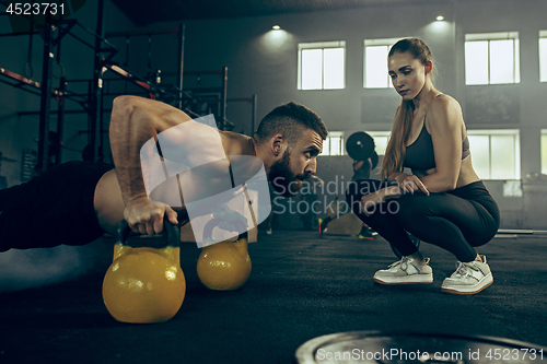 Image of Fit young man lifting barbells working out in a gym