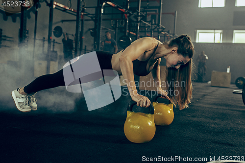 Image of Fit young woman lifting barbells working out in a gym