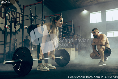 Image of Fit young woman lifting barbells working out in a gym