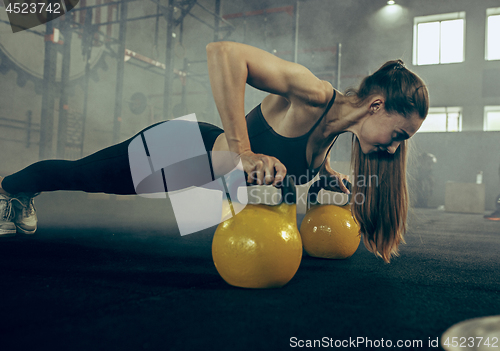 Image of Fit young woman lifting barbells working out in a gym