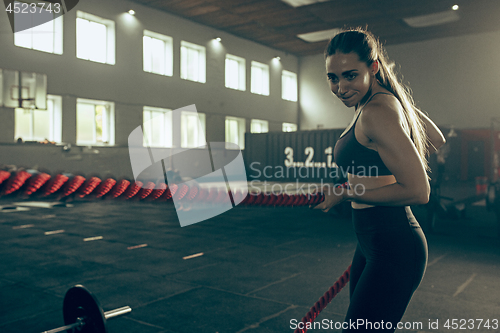 Image of Woman with battle ropes exercise in the fitness gym.