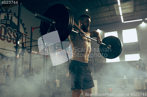 Image of Fit young man lifting barbells working out in a gym