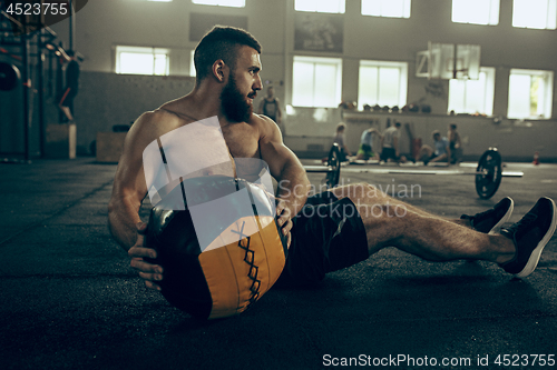 Image of Fit young man lifting barbells working out in a gym