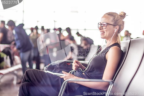 Image of Female traveler using her cell phone while waiting to board a plane at departure gates at asian airport terminal.