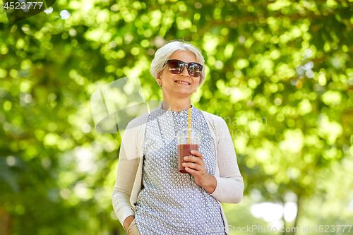 Image of senior woman drinking takeaway shake at park