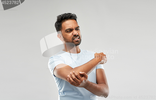 Image of unhappy man suffering from pain in hand