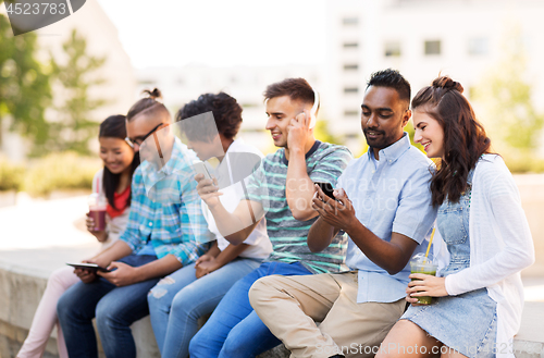 Image of friends with smartphones hanging out in summer