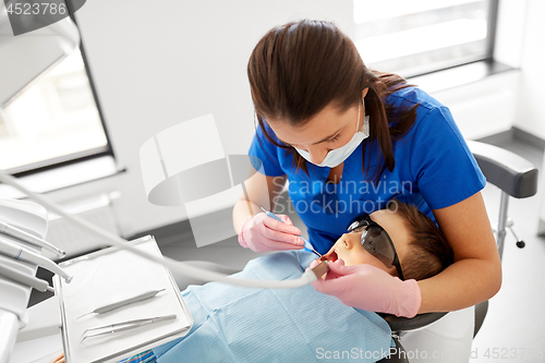 Image of dentist checking for kid teeth at dental clinic