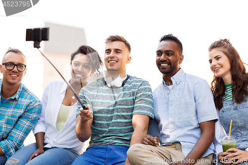 Image of friends taking picture by on selfie stick in city