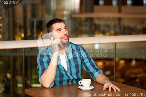 Image of man with coffee calling smartphone at restaurant