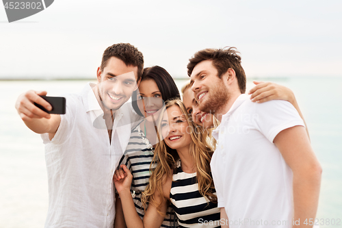 Image of happy friends taking selfie on summer beach