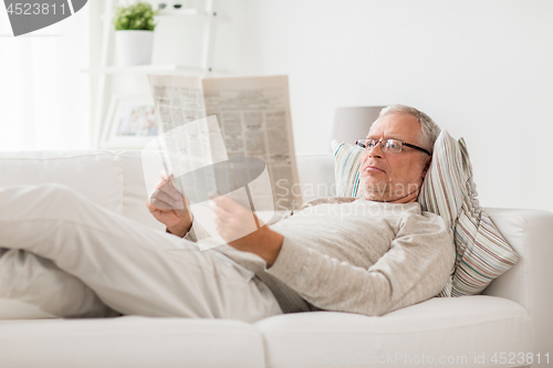 Image of senior man reading newspaper at home