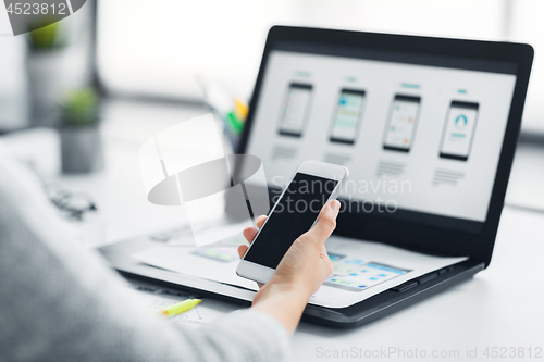 Image of web designer with smartphone and laptop at office