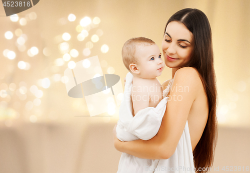 Image of close up of mother with baby over christmas lights