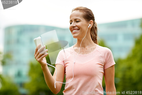 Image of woman listening to music on smartphone at park