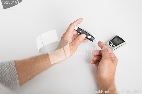 Image of senior man with glucometer checking blood sugar