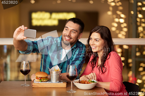 Image of couple taking selfie by smartphone at restaurant