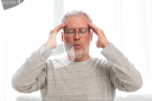 Image of senior man suffering from headache at home