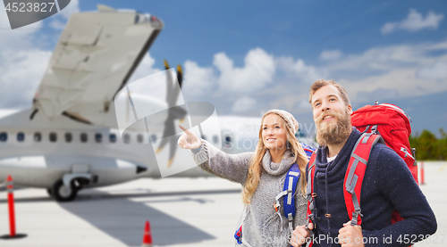 Image of couple of tourists with backpacks over plane