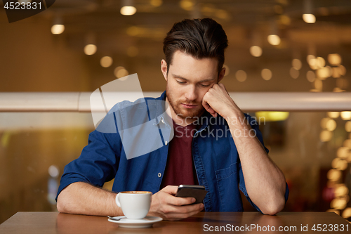 Image of sad man with coffee and smartphone at restaurant