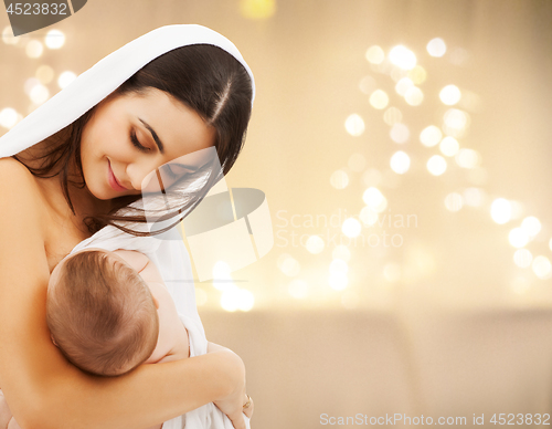 Image of close up of mother with baby over christmas lights