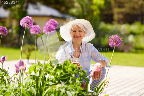 Image of senior woman with garden pruner and flowers