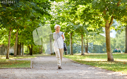 Image of senior woman calling on smartphone in summer park