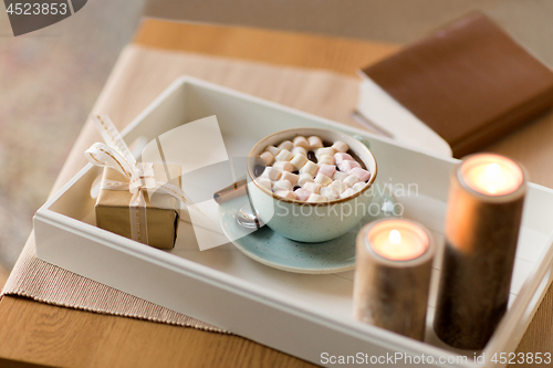 Image of hot chocolate, christmas gift and candles on table