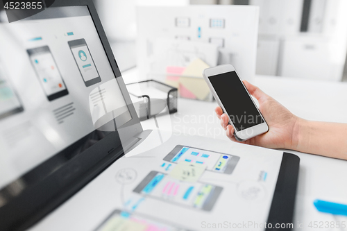 Image of web designer with smartphone and laptop at office