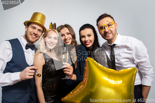 Image of happy friends with golden party props posing