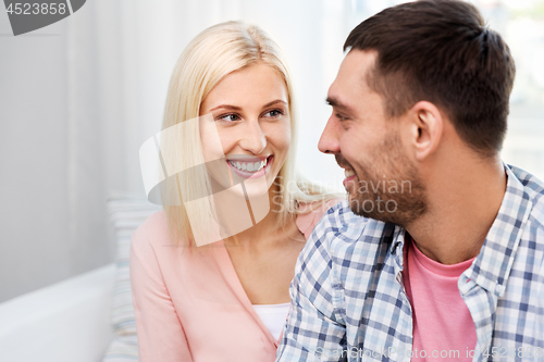 Image of smiling happy couple hugging on sofa at home