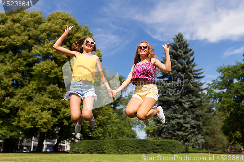 Image of happy teenage girls jumping at summer park