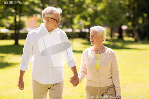 Image of happy senior couple walking at summer park