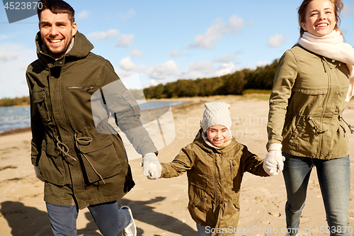 Image of happy family walking along autumn beach