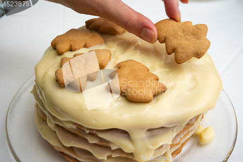 Image of Homemade cake with condensed milk, a hand on top puts a Christmas tree cookie