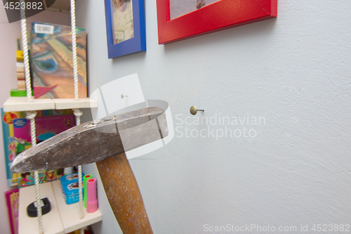 Image of A hammer hammers a nail into the wall, hanging frames with photos