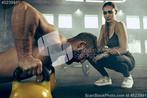 Image of Fit young man lifting barbells working out in a gym