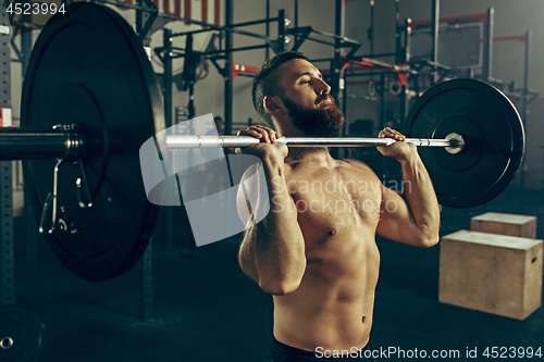 Image of Fit young man lifting barbells working out in a gym