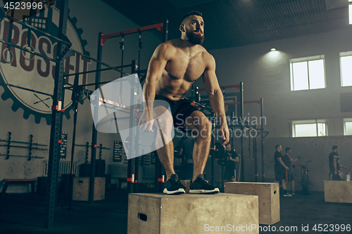 Image of Man jumping during exercises in the fitness gym. CrossFit.