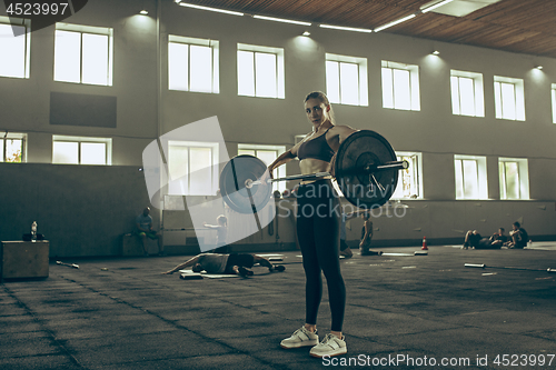 Image of Fit young woman lifting barbells working out in a gym