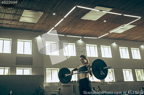 Image of Fit young woman lifting barbells working out in a gym