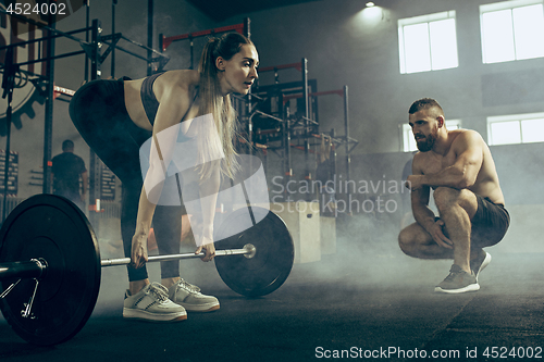 Image of Fit young woman lifting barbells working out in a gym