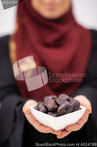 Image of modern muslim woman holding a plate of dates in ramadan kareem