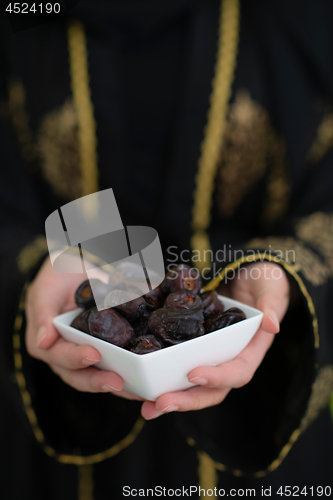Image of modern muslim woman holding a plate of dates in ramadan kareem