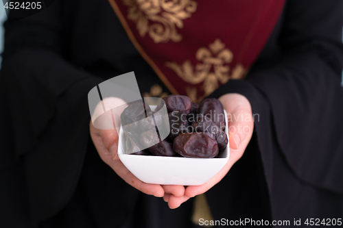 Image of modern muslim woman holding a plate of dates in ramadan kareem