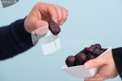 Image of modern muslim woman holding a plate of dates in ramadan kareem